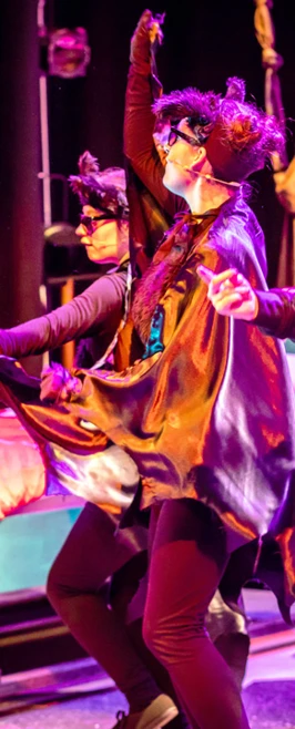 Performers dressed as playful cats and skeleton character dancing on a vibrant stage. Performers dressed as playful cats and skeleton character dancing on a vibrant stage.